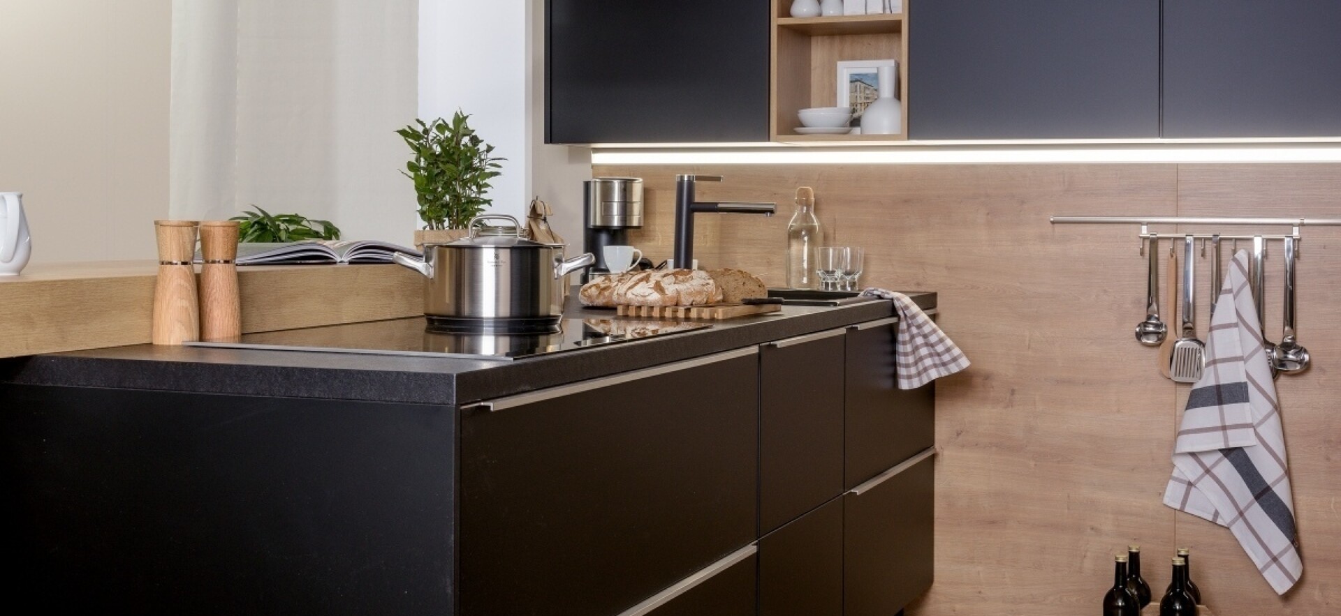 Küche in Schwarz, kombiniert mit Naturholz und Küchenunterschrank-Beleuchtung